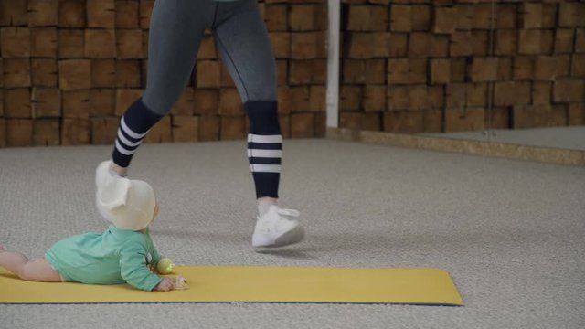 Mom does jumping with attacks during fitness together with the newborn.