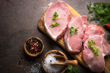 Fresh meat. Raw pork steak. Cooking ingredients. Top view over dark stone table.