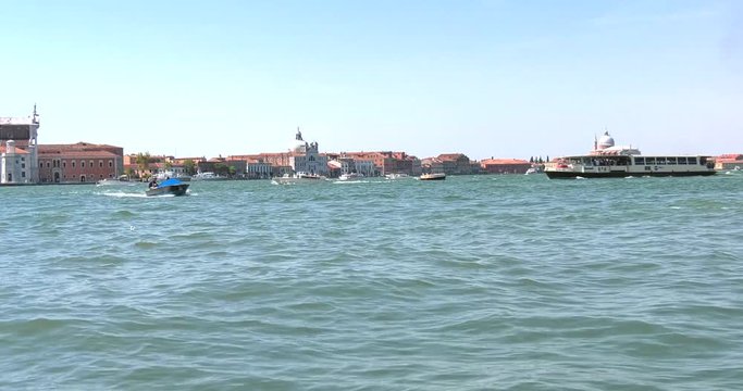 Barche lente e motoscafi trasportano persone nel canale di Venezia in Italia con mare adriatico poco mosso con piccole onde