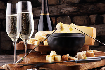 Gourmet Swiss fondue dinner on a winter evening with assorted cheeses on a board alongside a heated...