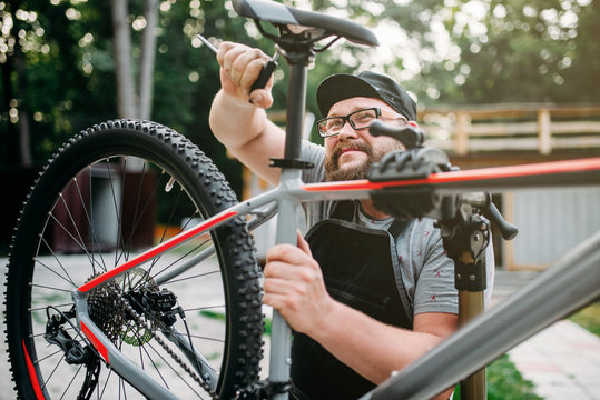 Bicycle mechanic adjusts with tools bike seat