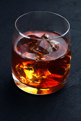 whiskey with ice in glass on a dark background
