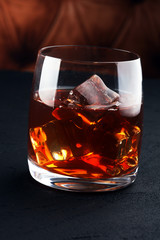 whiskey with ice in glass on a dark background