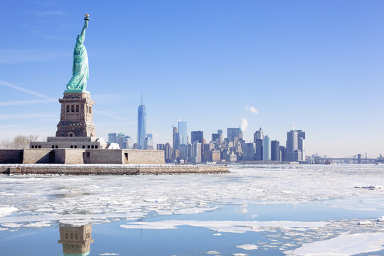 The city is frozen but the Statue of Liberty stands tall. Polar vortex, climate change.
