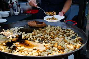 The cook prepares food in a huge frying pan in the open air.