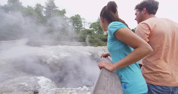 Tourists sightseeing New Zealand Waiotapu Rotorua Geothermal Area. Happy tourist couple looking at mudpot fumarole having fun visiting North Island of New Zealand. RED EPIC SLOW MOTION.