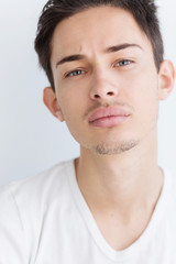 Portrait of a young man with dark hair and light eyes. on a white background. The guy in the white T-shirt. Male model.