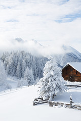 Alpenlandschaft. Urige Bergh&uuml;tte im Schnee und Berge im Hintergrund