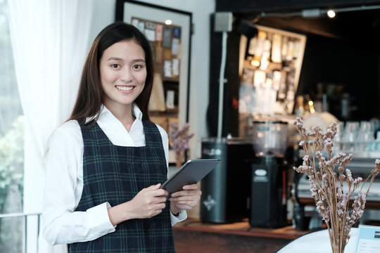 Young asian woman using tablet at cafe background, food and drink concept