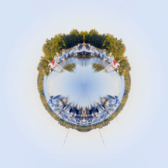 Planet effect of sailing and motorboats reflected in a lake and moored in a pier surrounded of trees