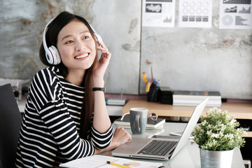 Obraz na płótnie Canvas Young office woman wearing wireless headphones relaxing while working, office lifestyles, people and technology