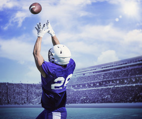 American Football Player Catching a touchdown Pass in a large outdoor football stadium