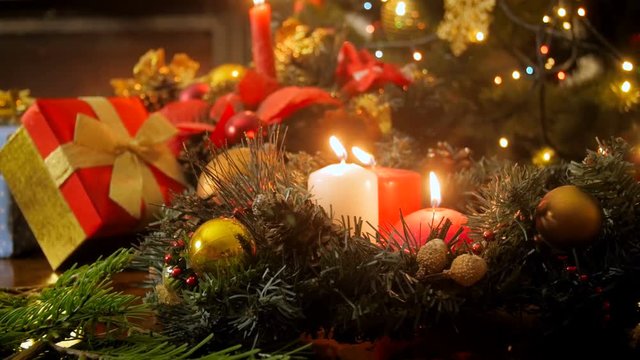 Closeup 4k dolly video of beautiful table full of gifts, ornaments, advent wreath and burning candles at living room with fireplace