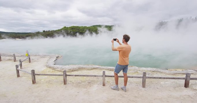 New Zealand travel tourist taking phone picture of famous attraction Champagne pool, Waiotapu. Active geothermal area, Okataina Volcanic Centre, Reporoa, in Taupo Volcanic Zone, Rotorua, north island.