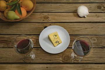 Wine and cheese testing, color grade WARM. Red wine, cheese, fruits on outdoor table. See the same image with color grade COLD