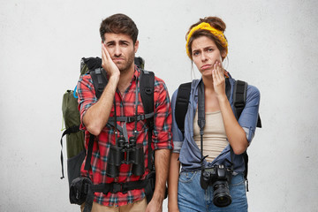 Studio shot of stylish young male and female hipster tourists or hitchhikers holding hands on their...
