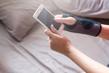 Women play mobile while elastic wrist support on hand to relieve pain
