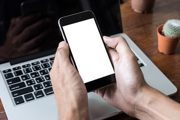 Man hand holding cellphone with blank screen mobile on wooden desk at coffee shop. Graphic display montage.