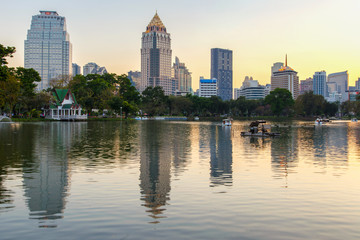Fototapeta na wymiar Business district cityscape from a park with sunset time from Lumpini Park, Bangkok, Thailand