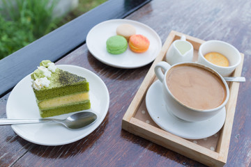 hot coffee breakfast set with green tea cake and fresh .macaroon in cozy outdoor cafe