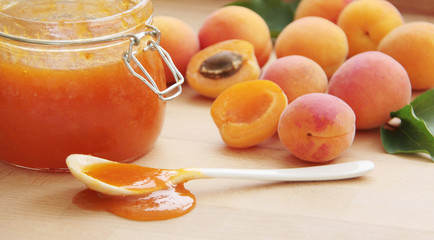 Fruity apricot jam in a glass jar. Fresh apricots on background. Close up view.