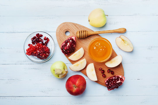 Honey, apple slices and pomegranate serve on kitchen board top view. Table set with traditional food for Jewish New Year Holiday, Rosh Hashana.