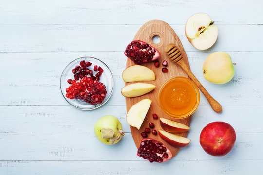 Honey, apple slices and pomegranate serve on wooden kitchen board overhead view. Table set with traditional food for Jewish New Year Holiday, Rosh Hashana.