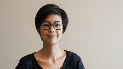 Asian woman  with short hair and glasses on color background