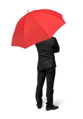 An isolated businessman standing with his back turned under a red umbrella.