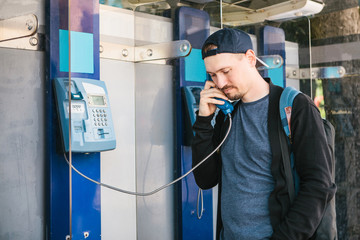 Young attractive modern man talking on the payphone