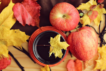 Autumn tea. Cup of tea with maple  autumn leaves, Apples and woolen rug on a wooden table.  Autumn style life