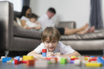 Fototapeta premium Caucasian boy play wooded toy in living room in home with his father and mother