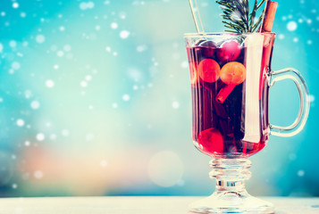 Mulled wine in cup with spices at winter day background with snow, front view, place for text