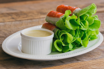 Fresh spring rolls with fresh vegetable and crab stick served with spicy salad cream dipping sauce. Rolls salad or fresh spring roll on white plate, healthy delicious food for appetizer or meal.