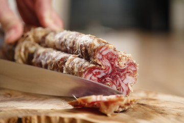 closeup shot of slicing salami with knife