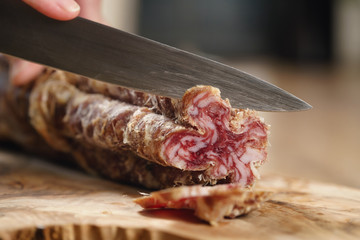 closeup shot of slicing salami with knife