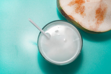 coconut with drinking straw, notebook and sunglasses on blue background