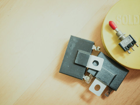 two black condensor and yellow soldering flux with texture wood background and copy space