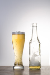 Glass of beer with bottle on the table.