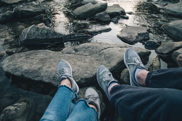 couple sits near mountain river and looking on sunset