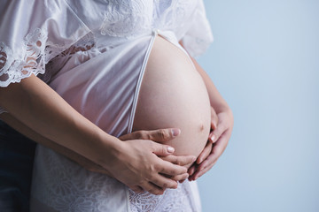 Mother and father hands holding pregnant belly. Third trimester of pregnancy