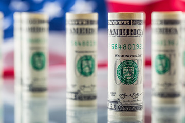 Dollar and American flag. American dollar banknotes rolled in different positions and USA flag in...