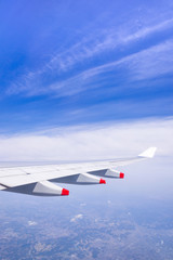 Flying into blue sky and city building on ground and Wing of airplane with skyline  top view as look from window airplane, during flight space for  text message, frame or traveling idea concept