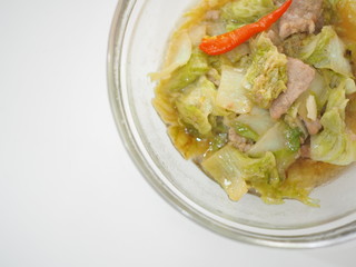 Thai local homemade stir fried chinese cabbage with pork and red chili, in glass bowl, white background