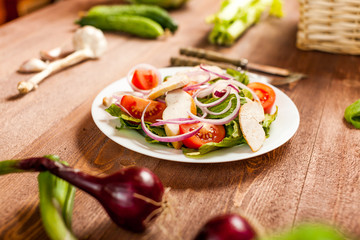 Fresh salad with chicken, tomato and greens on wooden background top view. Healthy food.