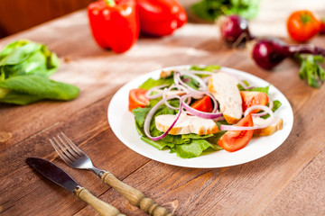Fresh salad with chicken, tomato and greens on wooden background top view. Healthy food.