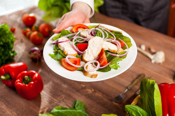 Fresh salad with chicken, tomato and greens on wooden background top view. Healthy food.