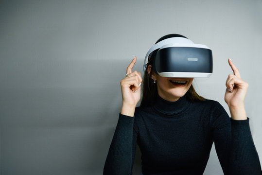 Picture of fascinated excited young brunette female wearing virtual reality modern glasses with head mounted display, entertaining herself, playing video games or watching something amazing