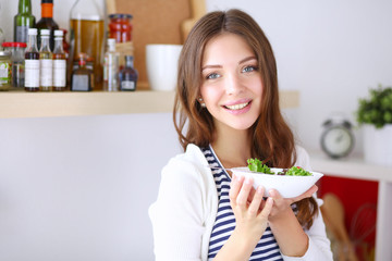 Young woman eating salad and holding a mixed