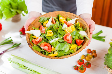 hands holding an healthy fresh vegetarian salad in a bowl